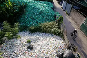 A Vietnamese woman drives past recyclable plastic bottles at Xa Cau village outside Hanoi