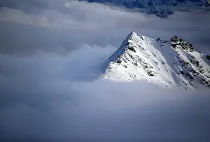 A view of a cross on a summit of the Goldberg group mountains as fog rises, seen