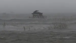 Philippines Prints: View of fishermans house in the middle of a fish pen as it is pounded by waves