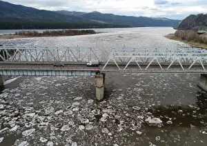 Environment Prints: A view shows vehicles driving along a bridge across the Mana River during an ice drift