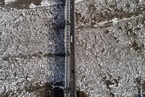 Environment Prints: A view shows vehicles driving along a bridge across the Mana River during an ice drift