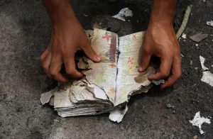 Guatemala Prints: A volunteer looks at a notebook with annotations recovered in an area affected by