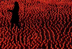 Volunteer sets up candles in shape of African continent at parliament square in Berne