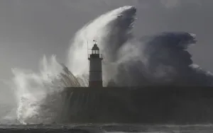 Waves crash against a lighthouse during storms that battered Britain