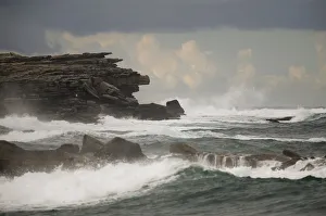 Waves hit a cliff on a rainy afternoon at Coogee beach in Sydney