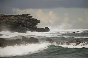Waves hit a cliff on a rainy afternoon at Coogee beach in Sydney