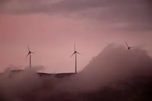 Wind turbines operate atop a mountain during sunset near the town of Kalavrita
