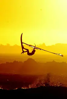 WINDSURFERS GETS AIRBOURNE AS THE SUN SETS ON CAPE TOWNs BLaUWBERG BEACH