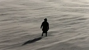 A woman braves the wind as she walks along New Brighton beach