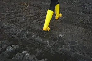 A woman with bright yellow boots walks though puddle of slush in Times Square during