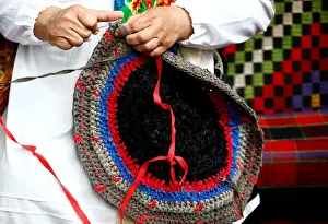 A woman knits a rug as she takes part in Beraginya festival of folklore art in the town