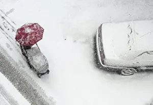 Ukraine Prints: A woman pushes her child in a pram, while walking under an umbrella during heavy snowfall