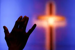 A woman raises her hand during a prayer service one day after the killing of five