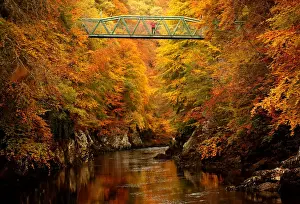 A woman stands on the footbridge over the river Garry near Pitlochry, Scotland