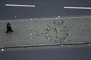 A woman takes pictures of flowers placed near the Christmas market in Berlin