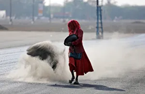 A woman throws a mixture of black ash, cement, concrete powder and ordinary dust over