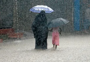 Images Dated 2018 May: A woman walks with a girl along a flooded road in the heavy rains in Malwana
