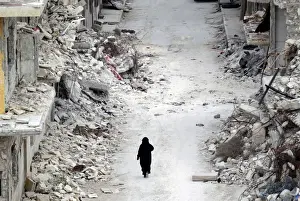 Mideast Prints: A woman walks past damaged buildings in the rebel-controlled area of Maaret al-Numan town