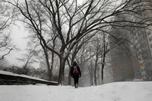 A woman walks in the snow next to Central Park along 5th avenue in upper Manhattan during