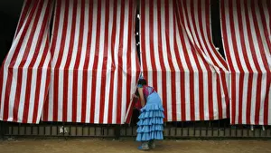A woman wearing a traditional Sevillana dress looks into a stall at a fair in Seville