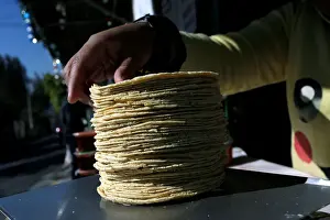Mexico Prints: Woman weighs a stack of freshly made corn tortillas at factory in Mexico City