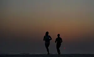 Women run during sunset on Barra da Tijuca beach in Rio de Janeiro
