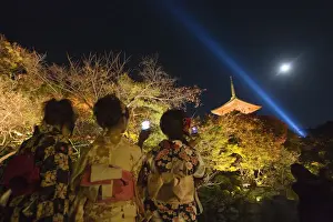 Women in traditional costumes take pictures during an evening light-up session inside