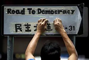 A worker removes masking tape left on road sign by pro-democracy protesters during