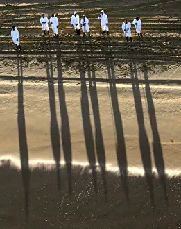 WORKERS CAST SHADOWS ON A CLEAN BEACH IN THE SPANISH NORTHERN COAST